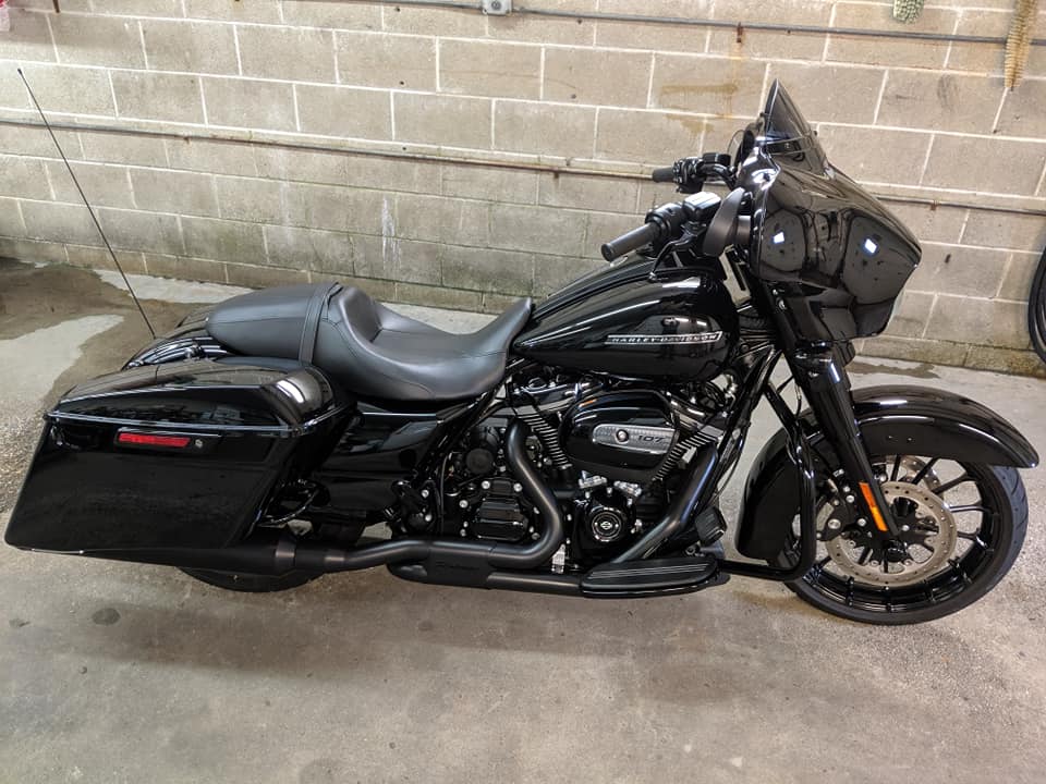 A black harley davidson motorcycle is parked in front of a brick wall.