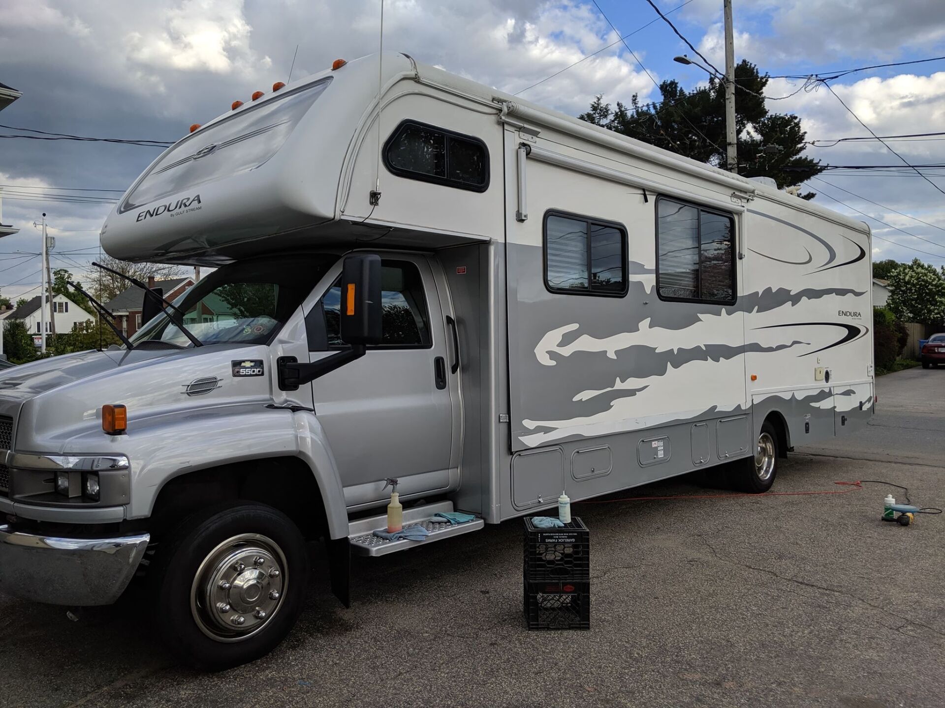 A silver and white rv is parked in a parking lot.
