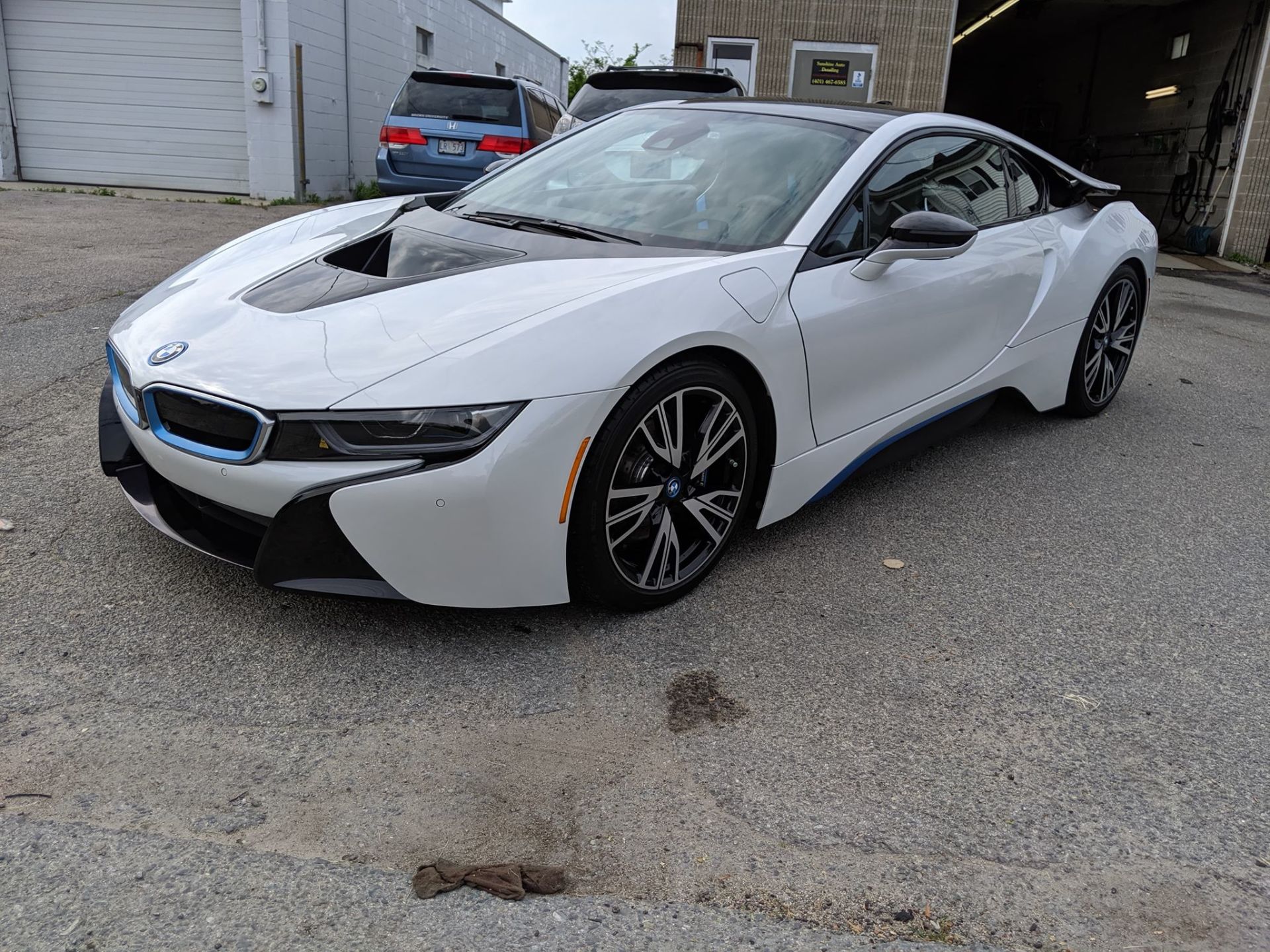 A white bmw i8 is parked in front of a garage.