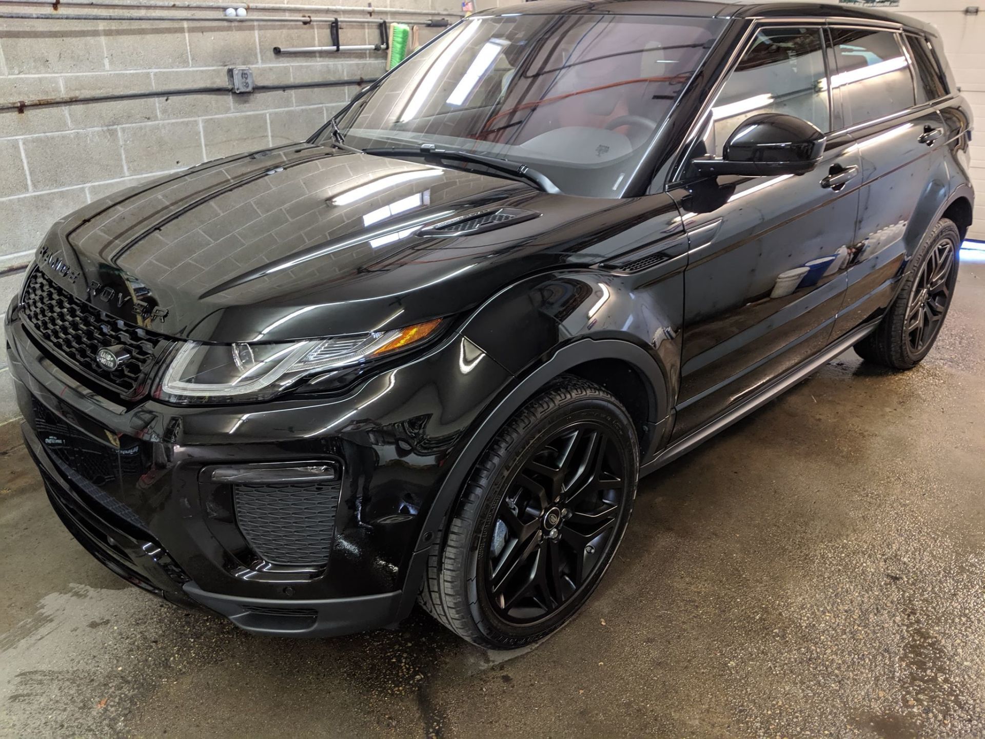 A black range rover evoque is parked in a garage.