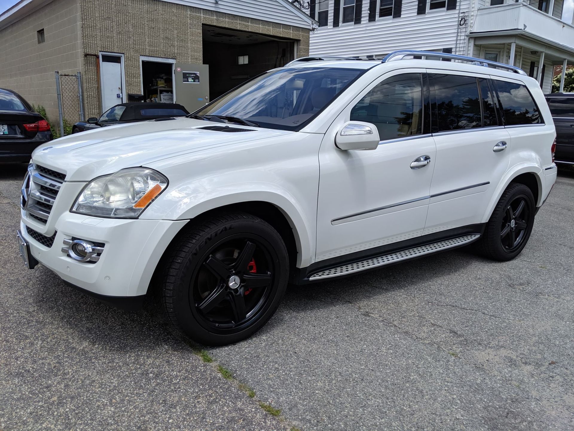 A white mercedes benz gl 550 is parked in front of a garage.
