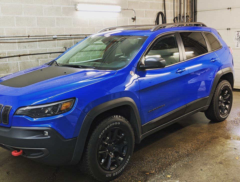 A blue jeep is parked in a garage next to a brick wall.