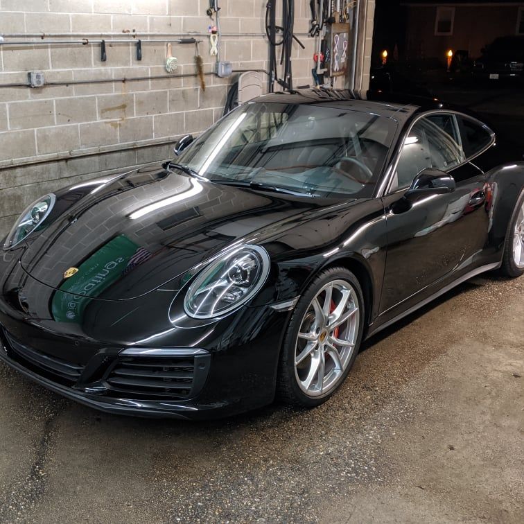 A black porsche 911 is parked in a garage.