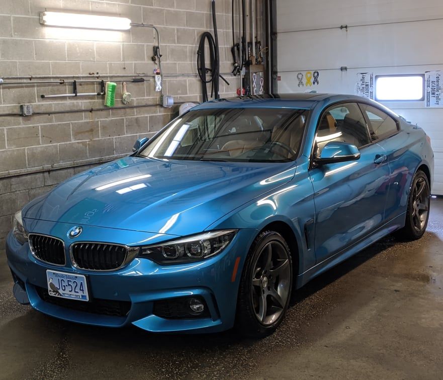 A blue bmw is parked in front of a garage door