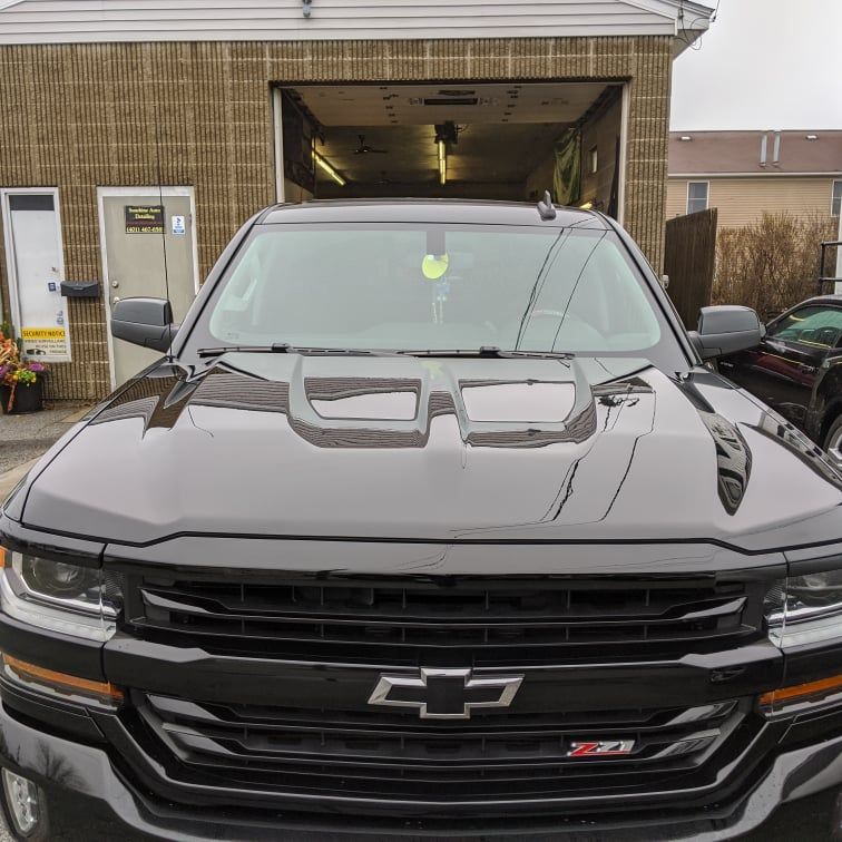 A black chevrolet truck is parked in front of a garage.