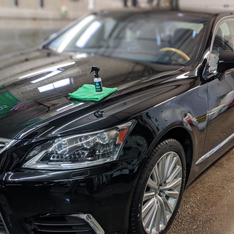 A black car with a spray bottle on the hood.