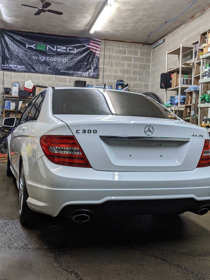 A white mercedes benz c300 is parked in a garage.