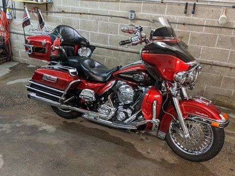 A red harley davidson motorcycle is parked in front of a brick wall