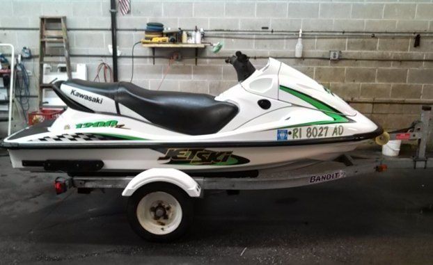 A white and green kawasaki jet ski on a trailer