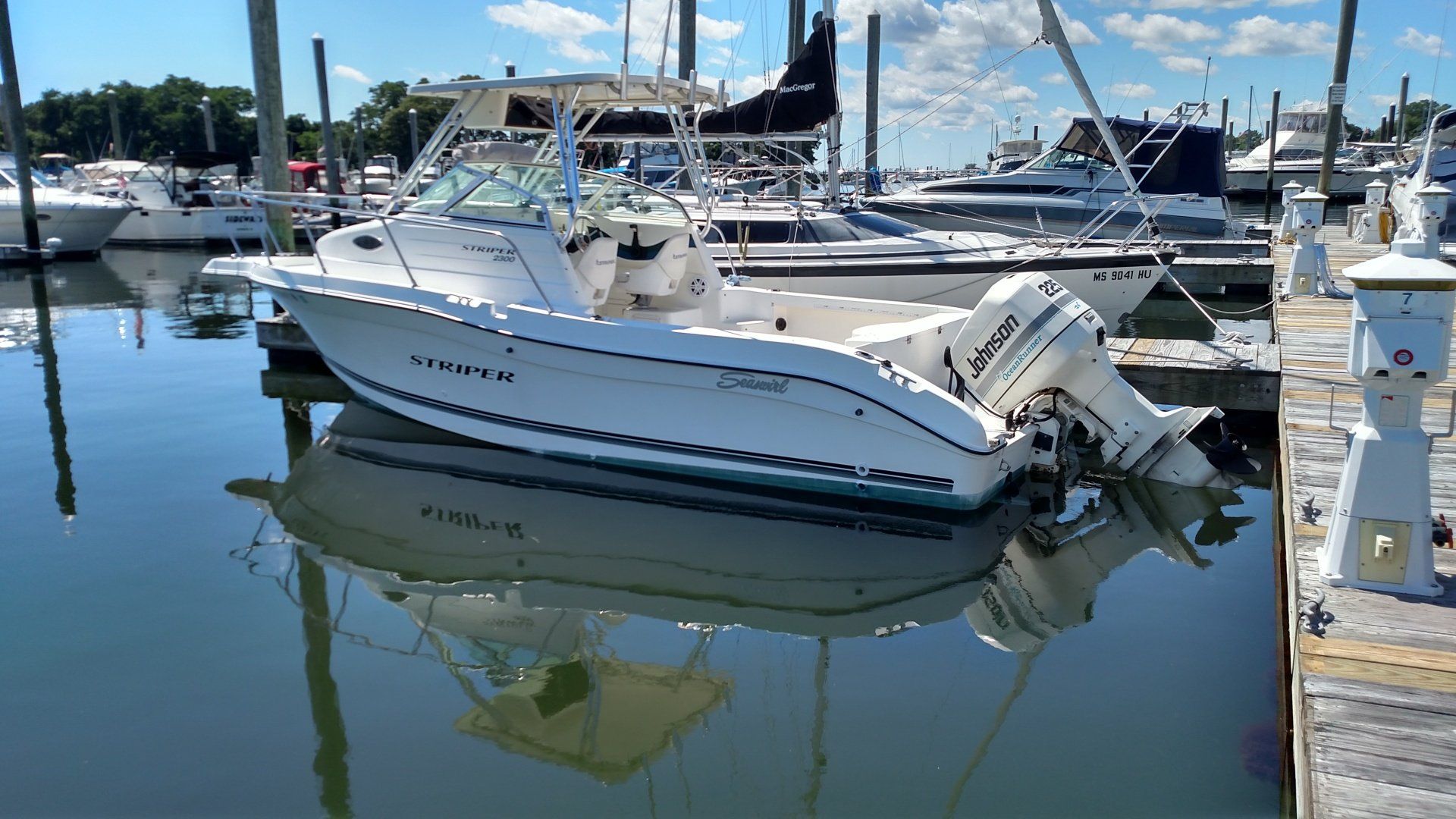 A white boat is docked at a marina next to a dock.