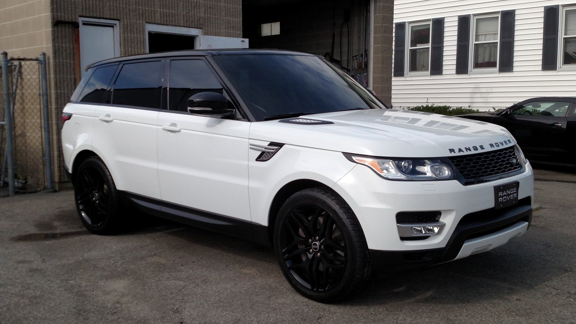 A white range rover sport is parked in front of a building.