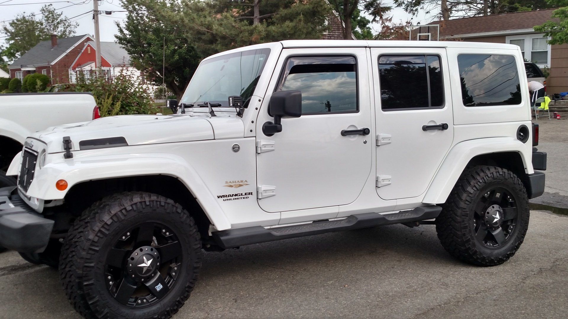 A white jeep with black wheels is parked in a parking lot.