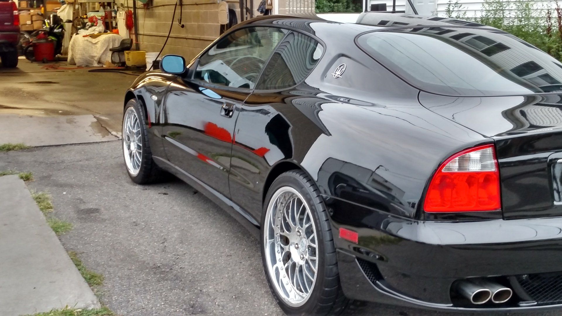 A black sports car is parked in front of a garage