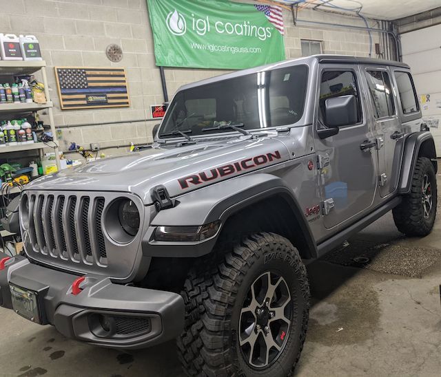 A silver jeep rubicon is parked in a garage.