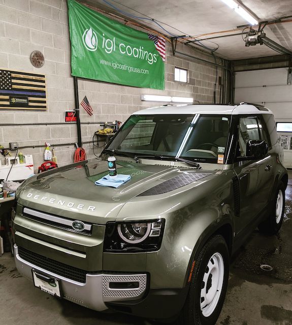 A green land rover defender is parked in a garage.
