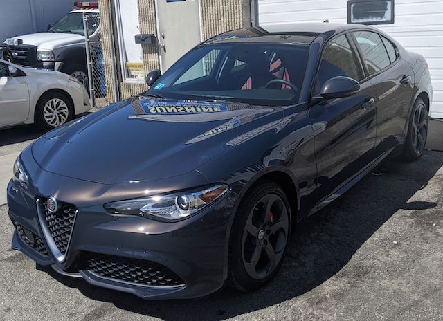 A gray car is parked in front of a garage.