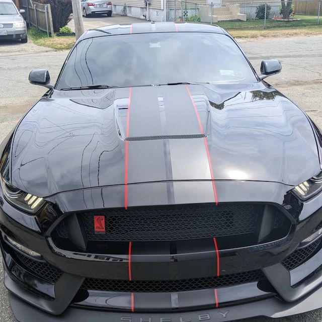 A black mustang is parked on the side of the road