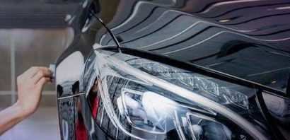 A person is applying a protective film to the hood of a car.