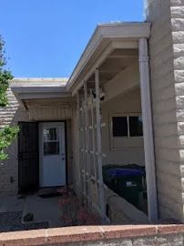 A house with a porch and a white door on a sunny day.