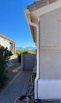 A house with a gutter on the side of it and a hose attached to it.