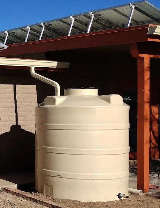 A large white water tank is sitting under a roof with solar panels.