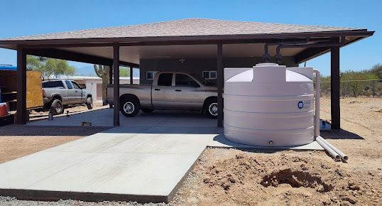 A truck is parked under a carport with a water tank in front of it.