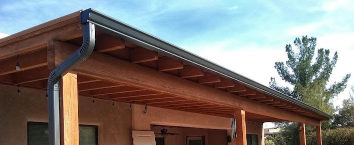 A porch with a wooden roof and a black gutter.