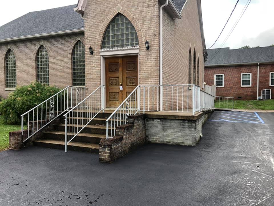 A church with stairs leading up to the door and a handicapped parking spot.