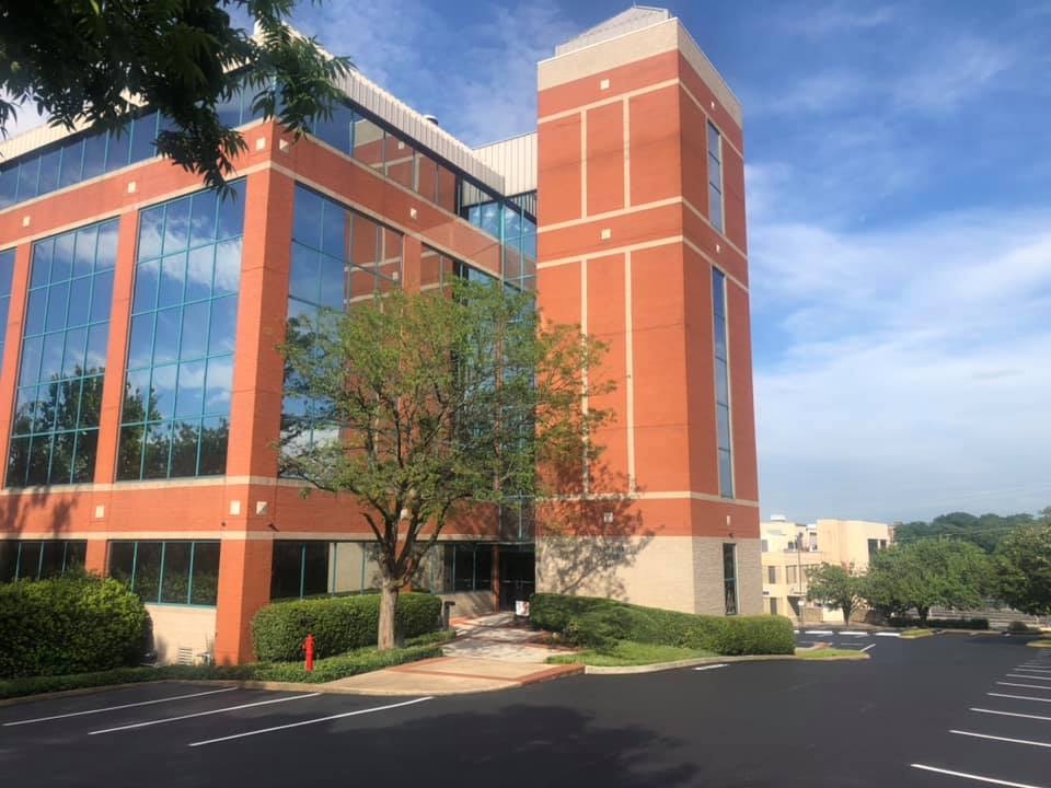 A large brick building with a lot of windows and a parking lot in front of it