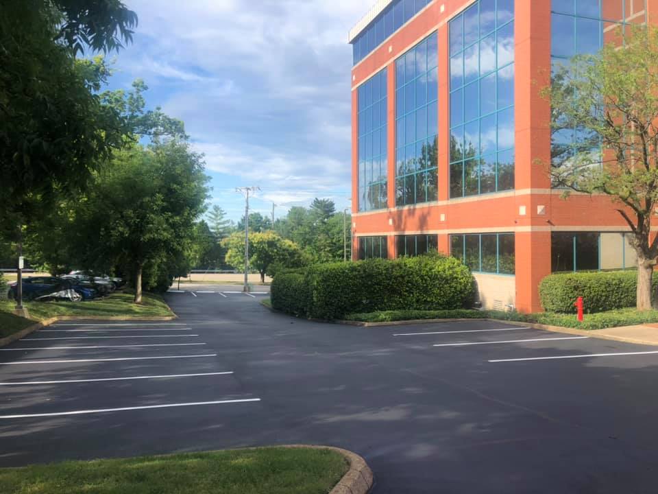 A large building with a lot of windows and a parking lot in front of it.