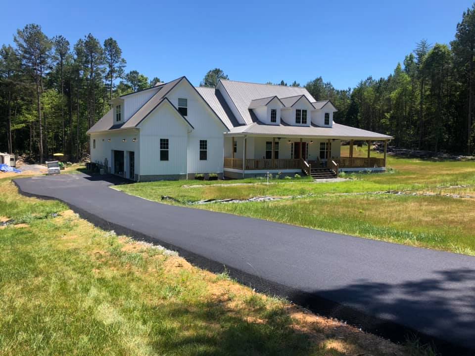 A large white house is sitting on top of a lush green field.