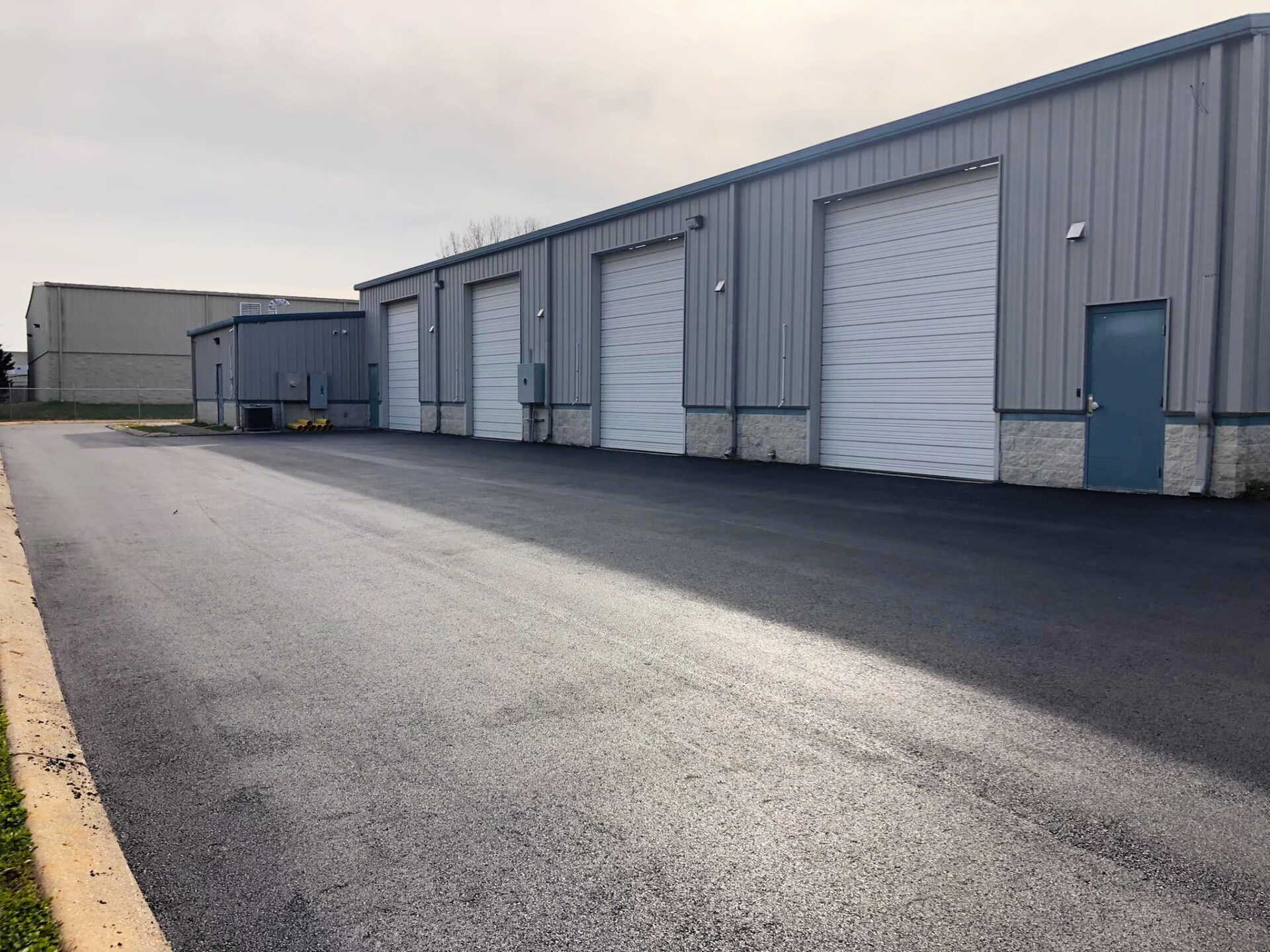 A row of garage doors are lined up next to a road.