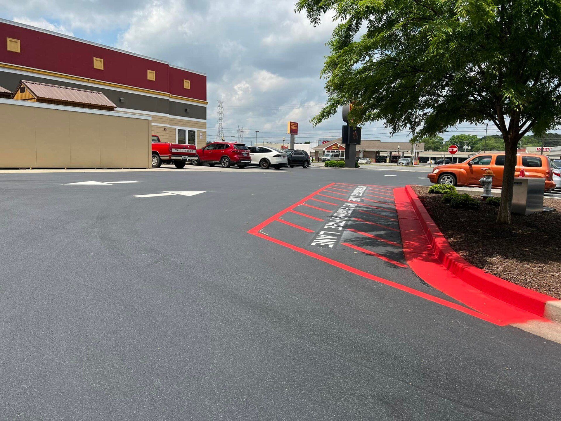 A parking lot with cars parked in front of a building and a red curb.
