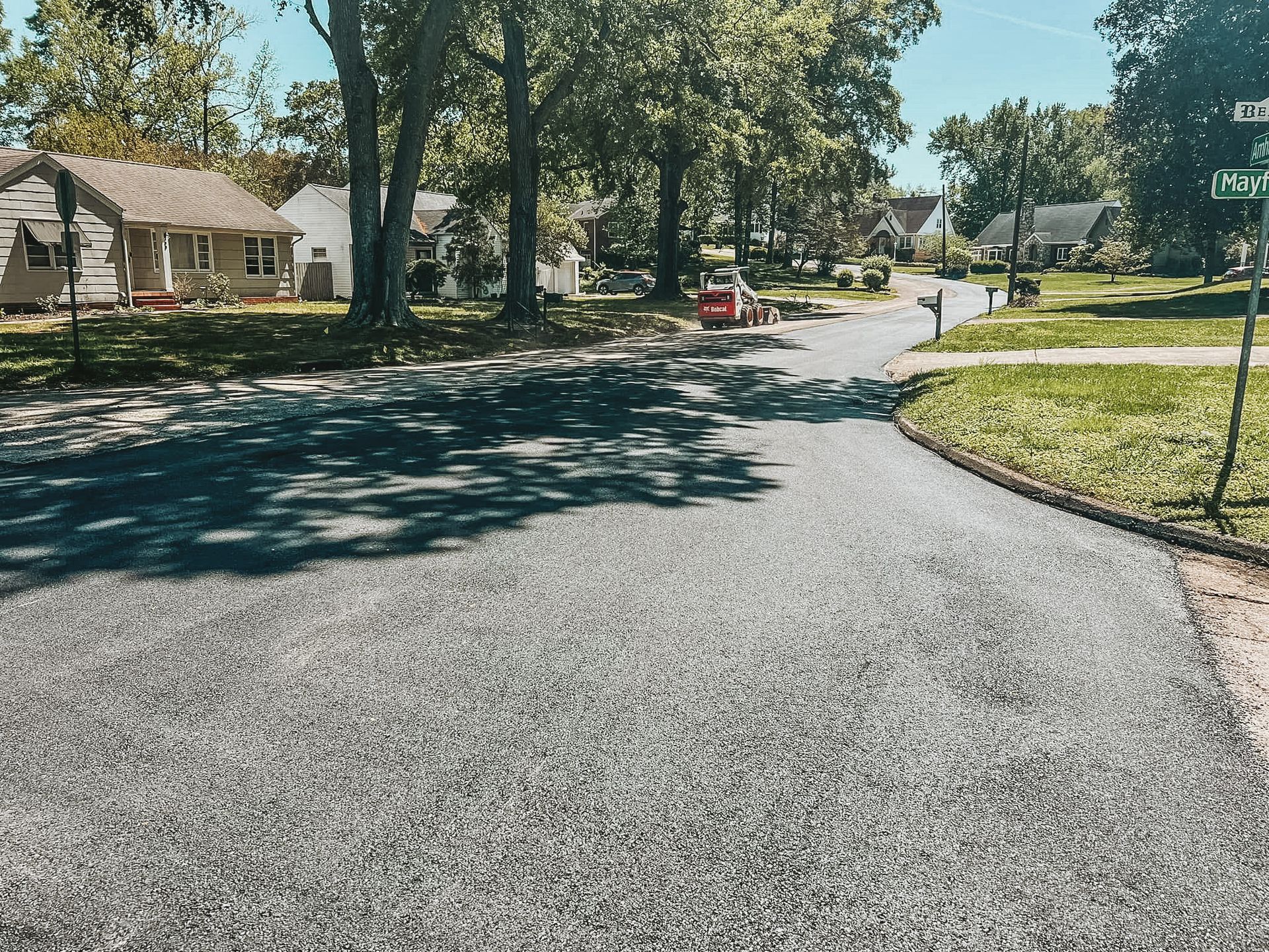 A residential street with a few houses and trees on the side of it.