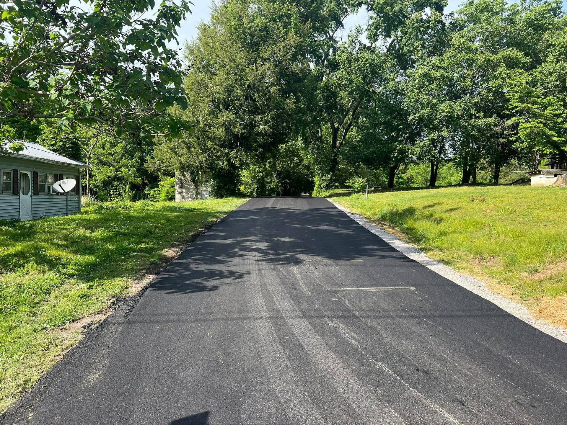 A black asphalt road going through a grassy field.