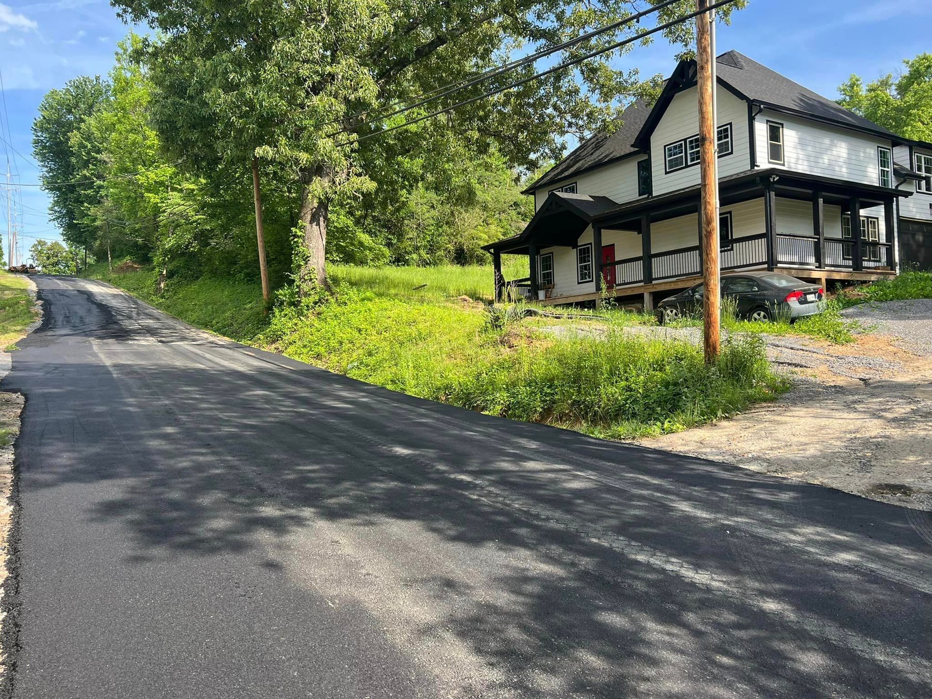 A house is sitting on the side of a road next to a telephone pole.