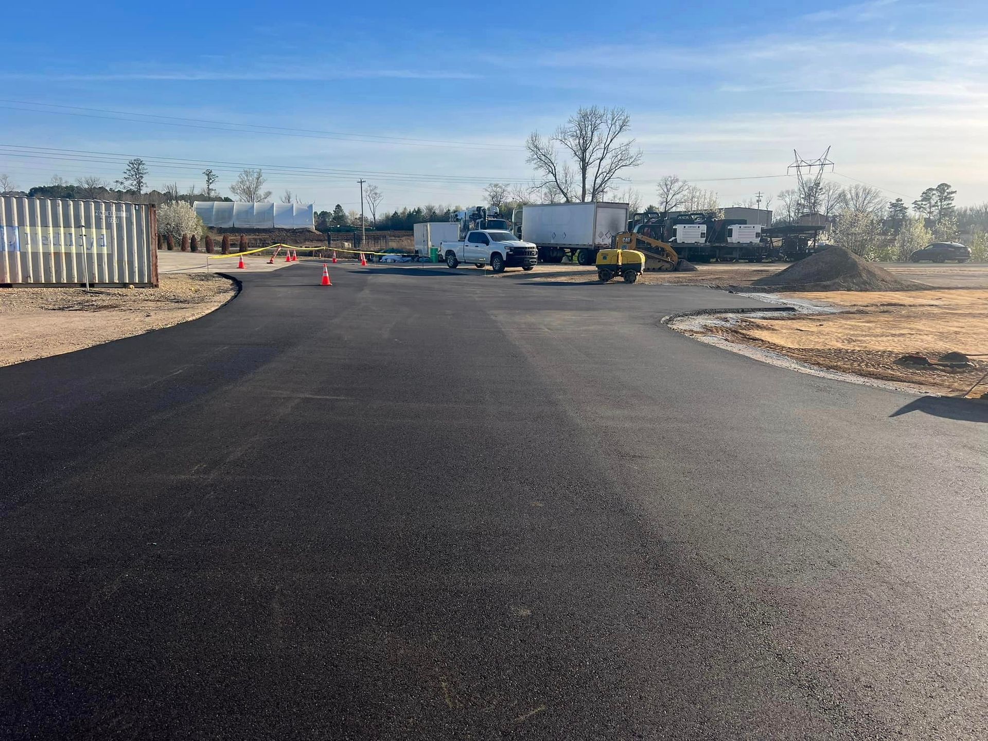 A black asphalt road with a lot of trucks parked on the side of it.