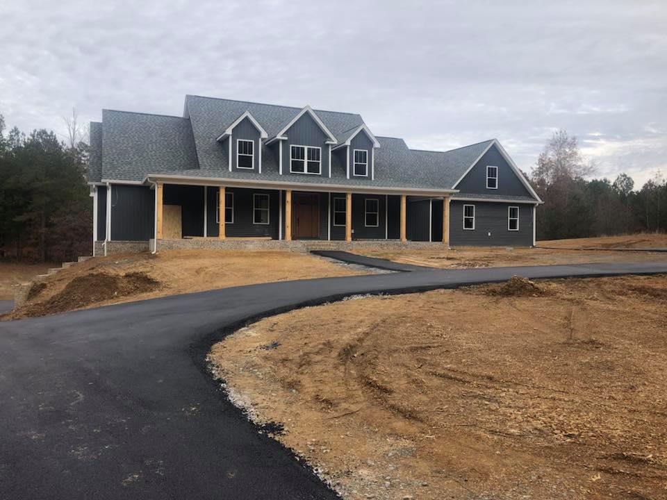 A large house is being built in the middle of a dirt field.