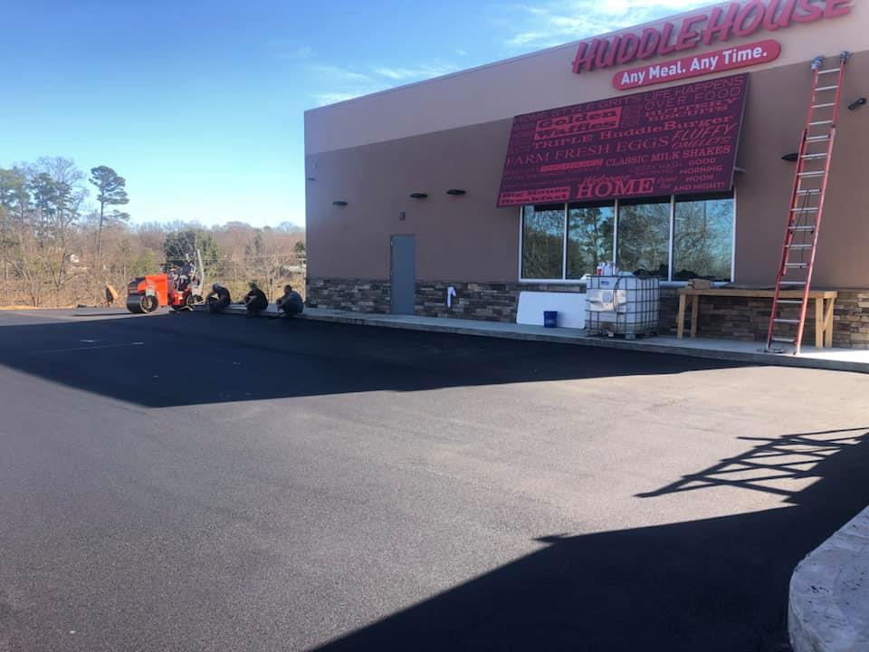 A group of people are working on a driveway in front of a building.