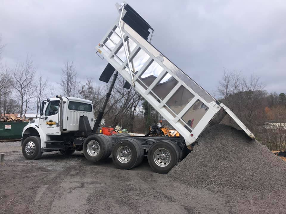 A dump truck is sitting on top of a pile of gravel.
