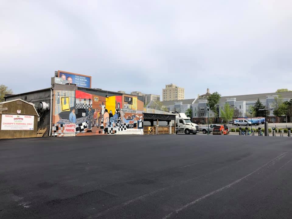 A large mural on the side of a building in a parking lot.