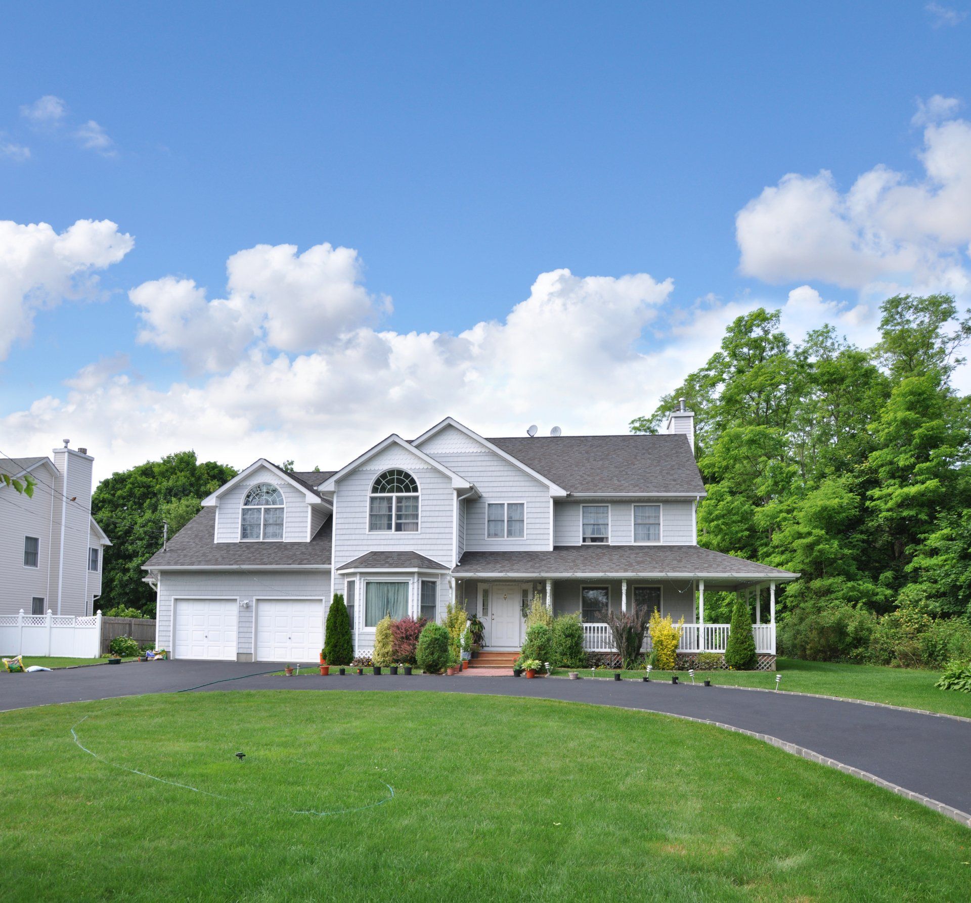 A large white house with a porch and a driveway