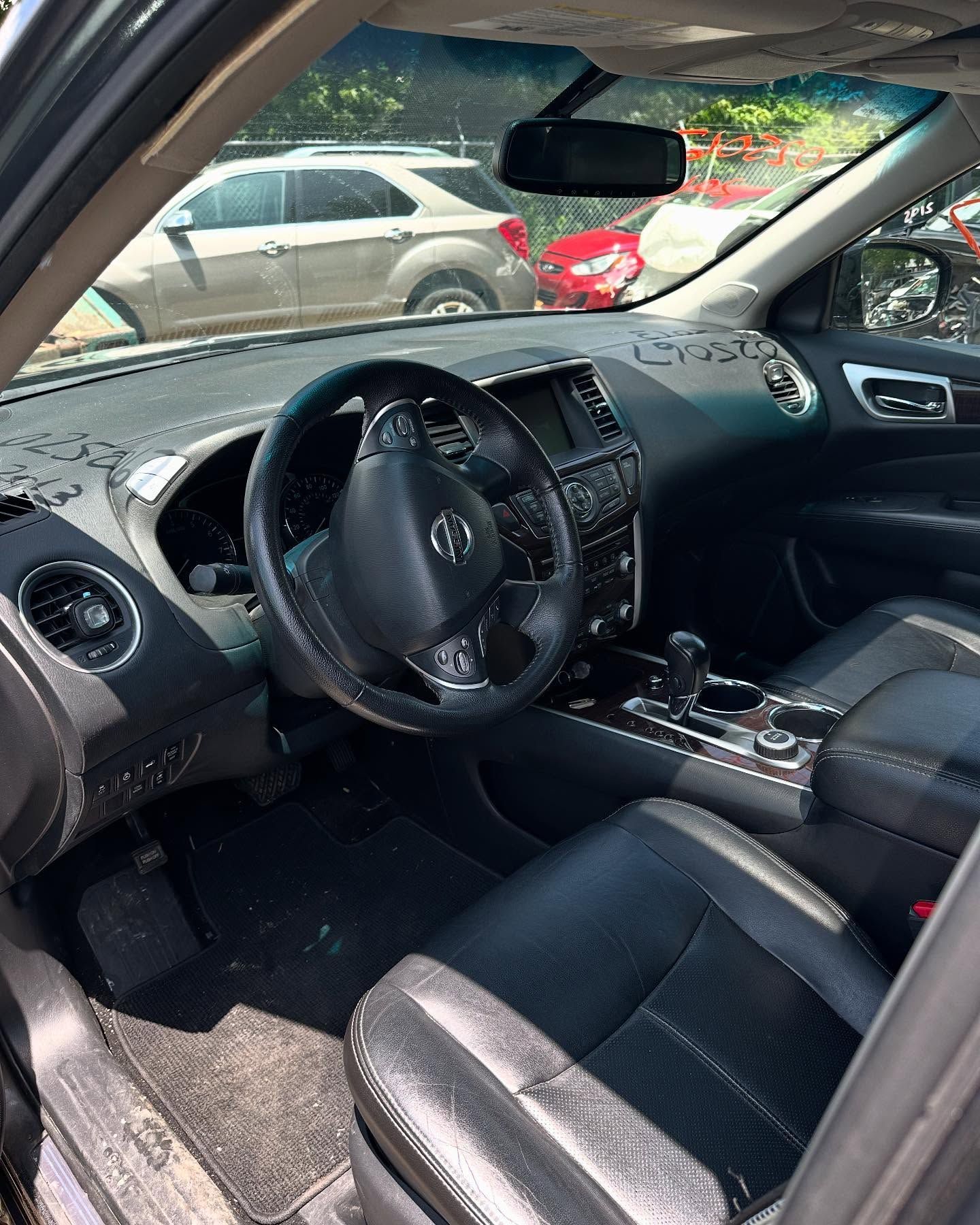 Interior of a black Nissan Pathfinder SUV showing the dashboard, steering wheel, and seats.