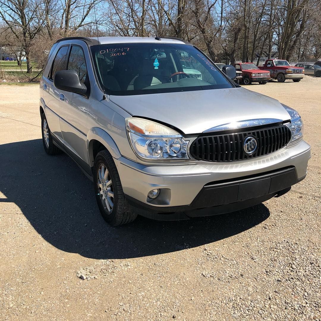 Silver Buick SUV parked on gravel in a sunny outdoor lot.