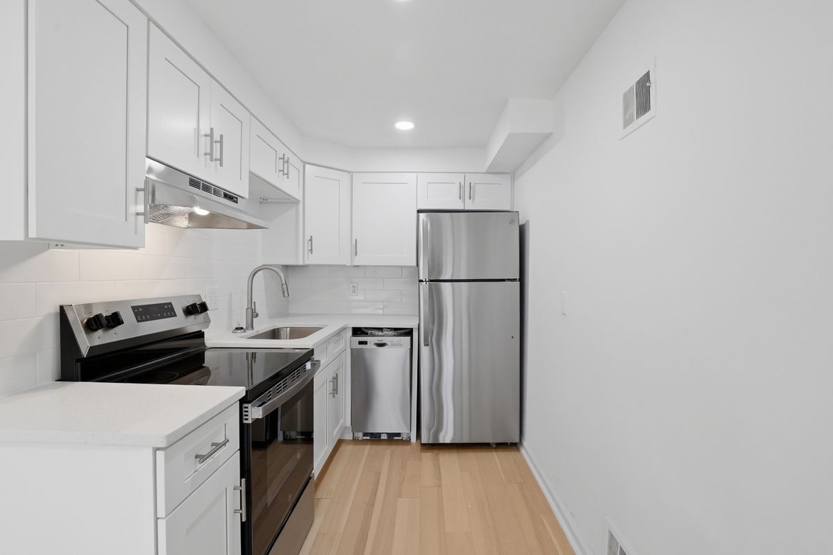 Living room with gray sofa, side table with lamp, and wooden cabinet with plants.
