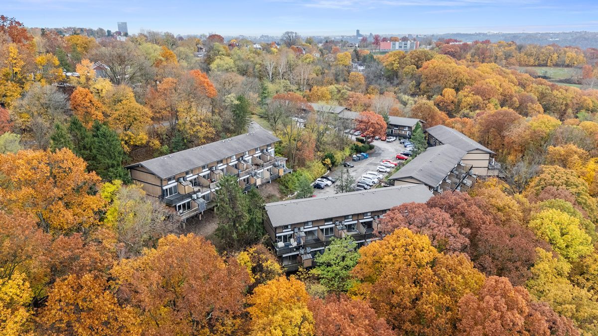 Aerial view of apartment buildings nestled among trees with vibrant autumn foliage.