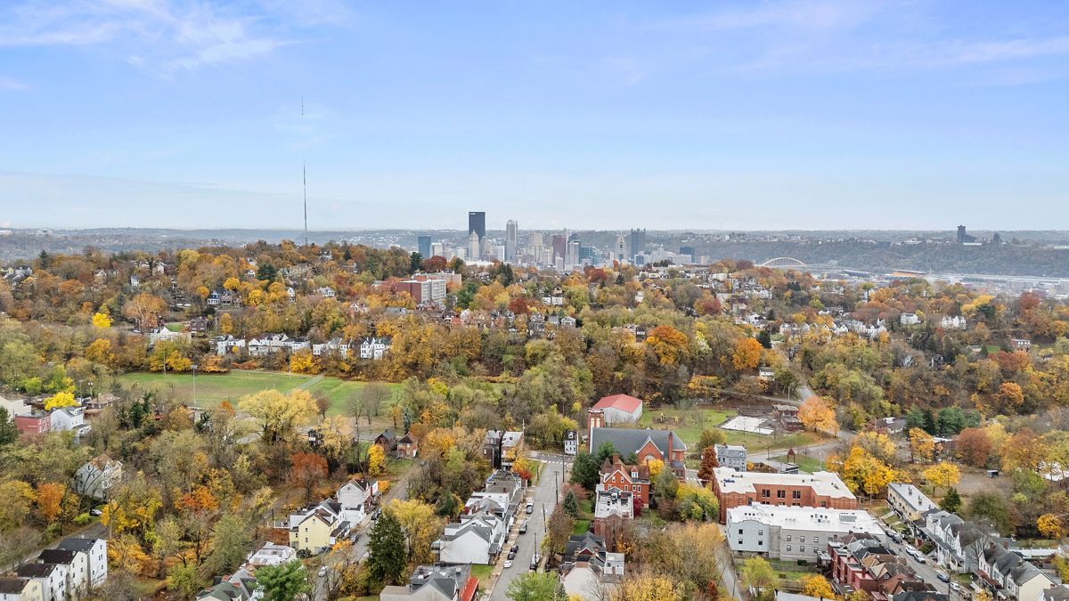 Fall foliage view of Cincinnati skyline. Homes and trees dominate the landscape. Blue sky.