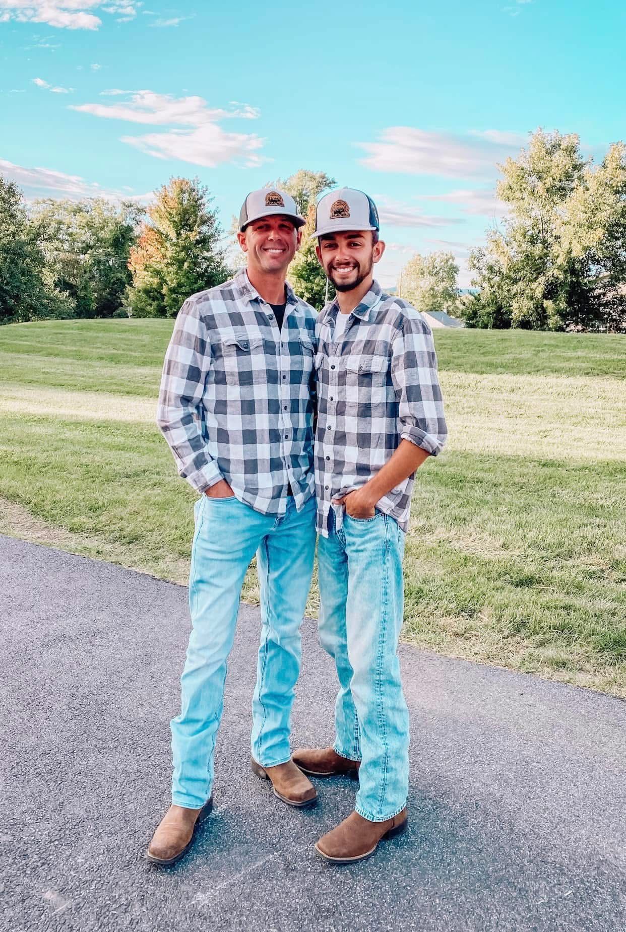 Person trimming the edge of a hedge with an electric trimmer outdoors on a sunny day.