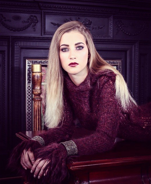 Woman with long blonde hair wearing rouge sweater