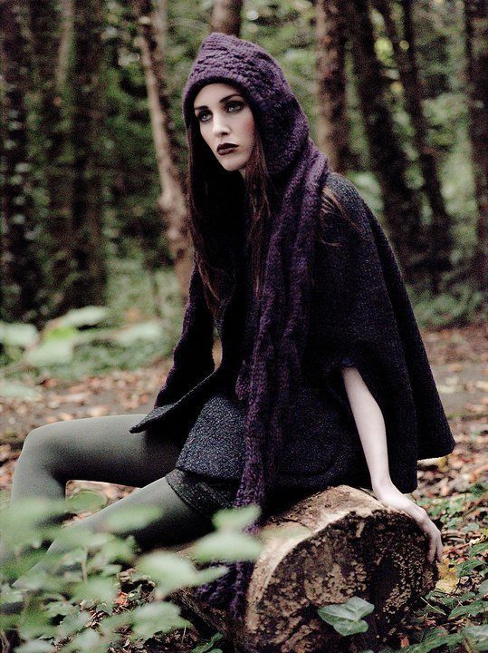 Woman sat in forest wearing purple hoodie and dark make-up
